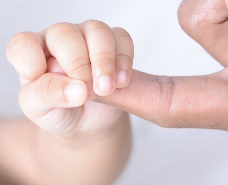 Hand eines Babys umfasst Finger eines Erwachsenen